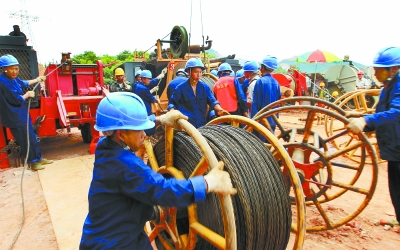 6月30日，湖南省电网工程公司的施工人员，在位于湘乡市山枣镇的±800千伏特高压输电线路施工现场架设电线。