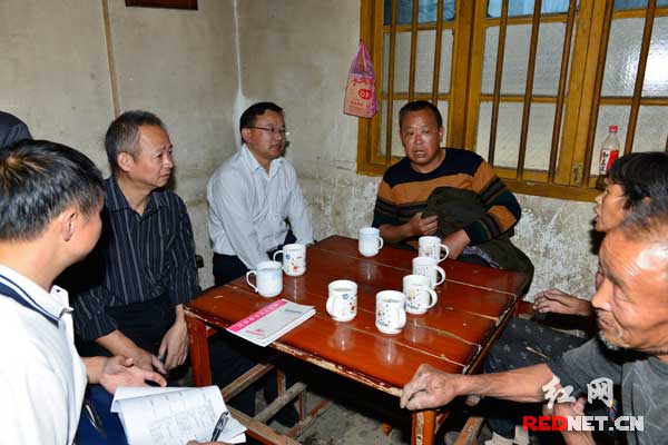 刘建华（左二）在农民家中与农民交谈。