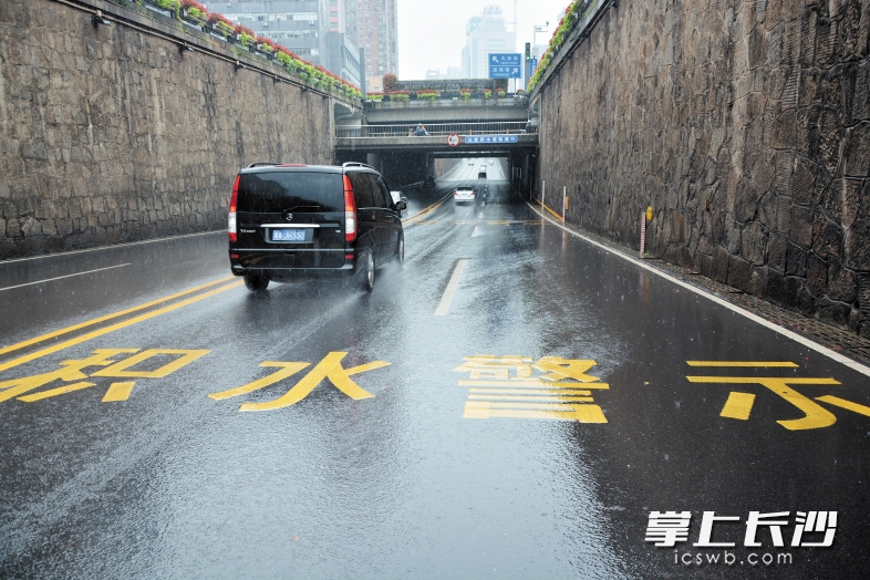 前日,天空正下着大雨,在袁家岭立交桥南北下穿车行通道,车辆从设置积水警示标识的涵洞安全通过。长沙晚报记者 王志伟 通讯员 周正 摄影报道