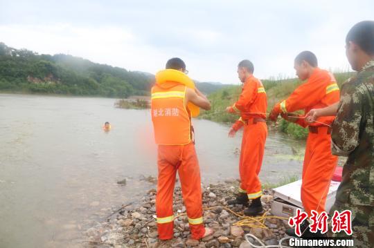 湖北远安两男子遭洪水围困消防“飞绳”救援（图）