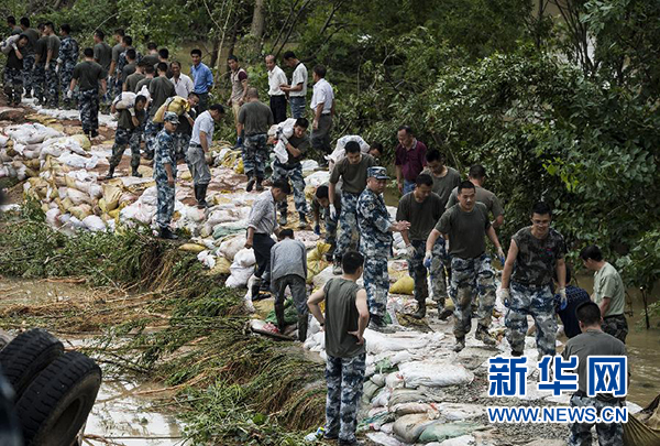 7月3日,中部战区空军航空兵某师的战士在新洲区沙河辛冲村段溃口处搬运防洪沙袋。新华社记者肖艺九摄