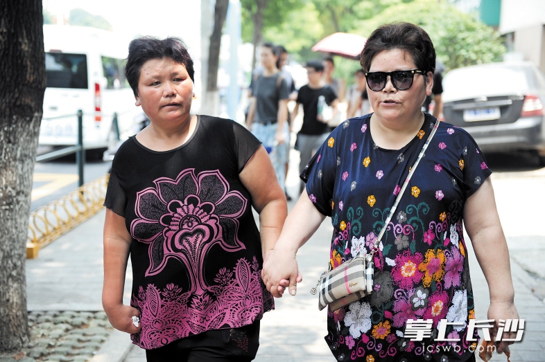 蒋月华姐妹两人牵手走在当年居住的街道上，找寻儿时的记忆。