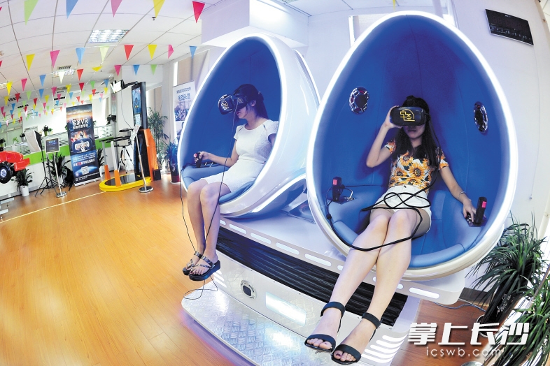 ↑昨日下午，湖南虚拟现实世界智能技术有限公司虚拟现实体验区内，市民在兴高采烈地体验VR产品。 长沙晚报记者 王志伟 摄