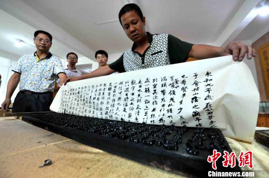图为四堡仅有两位雕版技艺代表性传承人之一的马力向记者展示历时3个月创作的《兰亭集序》雕版，并现场演示上墨、覆纸、印刷等一道道雕版印刷工序。张斌 摄