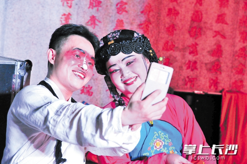演出间隙，两名演员在玩自拍发微信朋友圈。从他们的表情上，看不出高温炎热的难耐。均为长沙晚报记者 贺文兵 摄