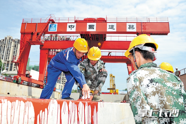 昨日上午，长沙市轨道交通4号线福元大桥西站施工现场，谷海华（左二）等在师傅李卓（左一）的指导下进行防水涂料施工。 