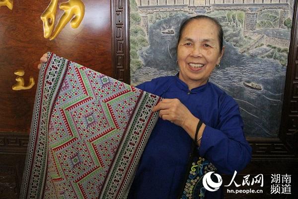 69岁的织娘石培云展示侗锦