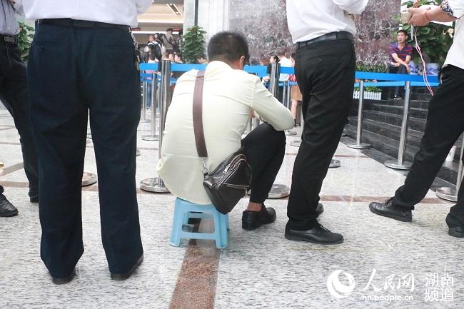 长沙不动产登记中心里，市民坐在随身携带的小板凳上