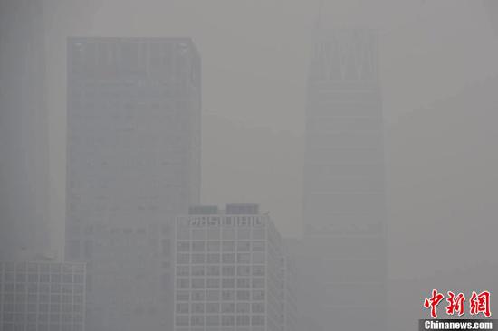 11月18日，北京城区因污染物扩散条件较差于17日发布的今冬首个雾霾橙色预警仍将持续。图为北京国贸CBD的高楼大厦若隐若现。中新网</a><p align=