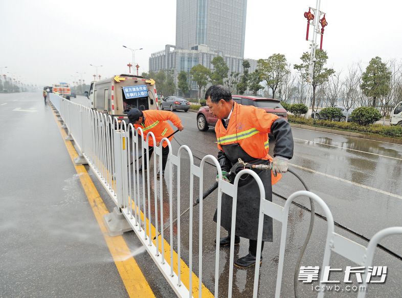 昨日下午，在青竹湖路上，开福区环卫工人正在清洗护栏，保障城市的干净整洁。 长沙晚报记者 邹麟 摄