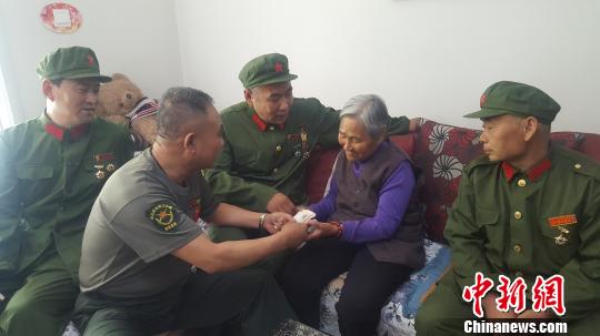 图为老兵们将慰问金送到门二柱母亲手中。吕新颖 摄