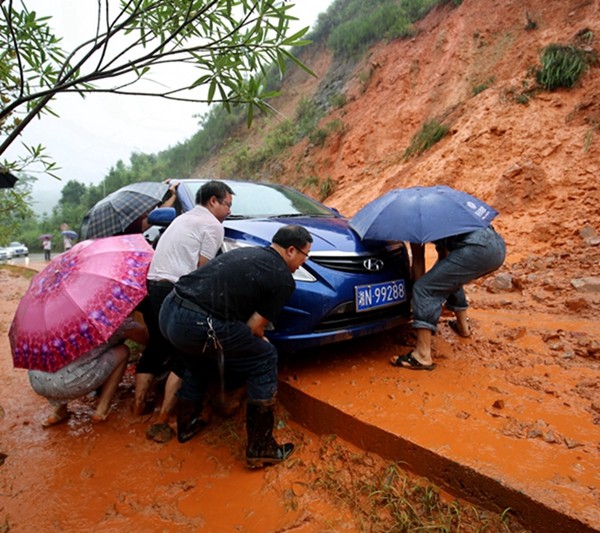 7月1日，209国道菁芜洲小江口段，干群齐心协力将陷入淤泥的轿车移走。