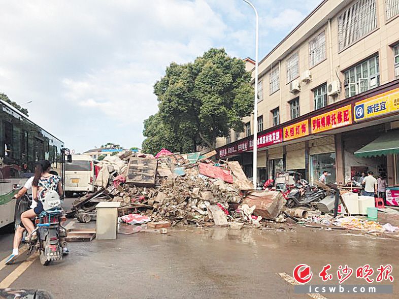 ←前日下午，白马大道的路边堆满了被水淹过的物品及各类垃圾，非常脏乱，车辆通行也受到影响。均为长沙晚报记者 周柏平 余劭劼 摄影报道