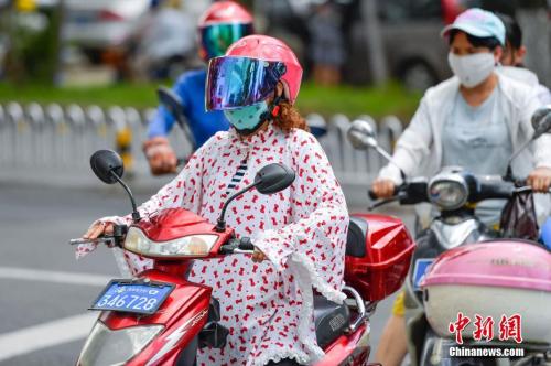 资料图：2017年6月5日，海口市民在高温下“全副武装”出行。中新社记者 骆云飞 摄