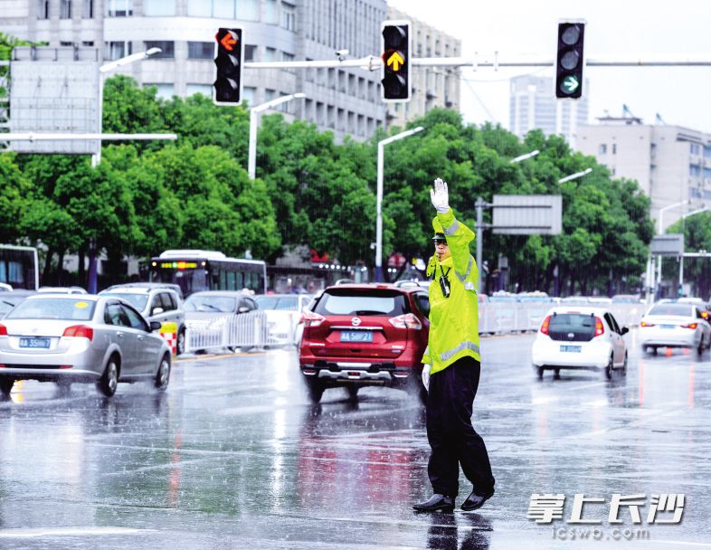 昨日下午，一场暴雨袭击长沙。由于降雨恰逢周日，上班的市民较少，因此，此次强降雨对长沙交通影响不大，城区道路交通基本畅通。图为车站北路口，一位交警正在雨中疏导交通。长沙晚报记者 刘琦 邹麟 摄影报道