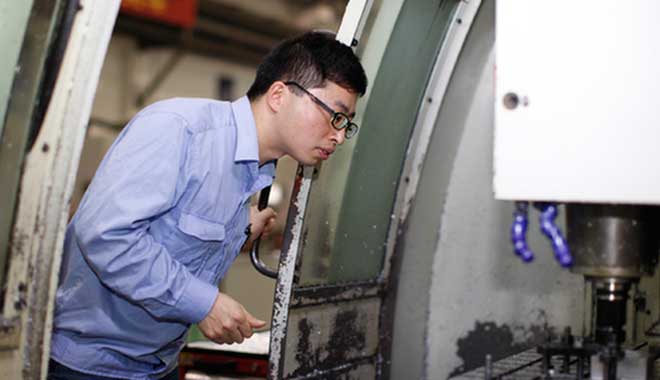 在铣削加工中心，陈闰祥正检查零件状况。 资料图