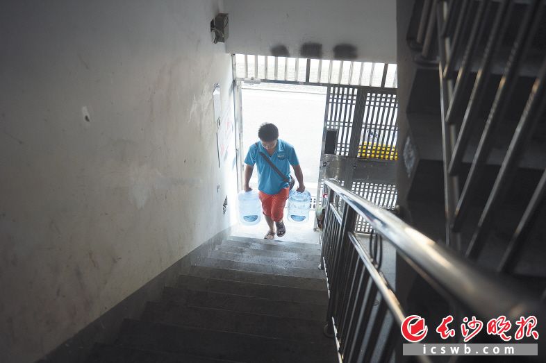 邱青松手提两桶水爬楼梯。均为长沙晚报记者余劭劼摄