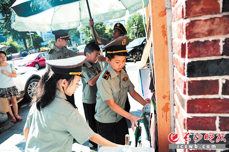 →小城管们正在帮商铺搬运占道经营的物品。长沙晚报通讯员 彭红霞 摄