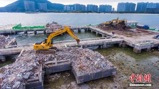 资料图：执法部门工作人员清理拆除后的建筑垃圾。 骆云飞 摄