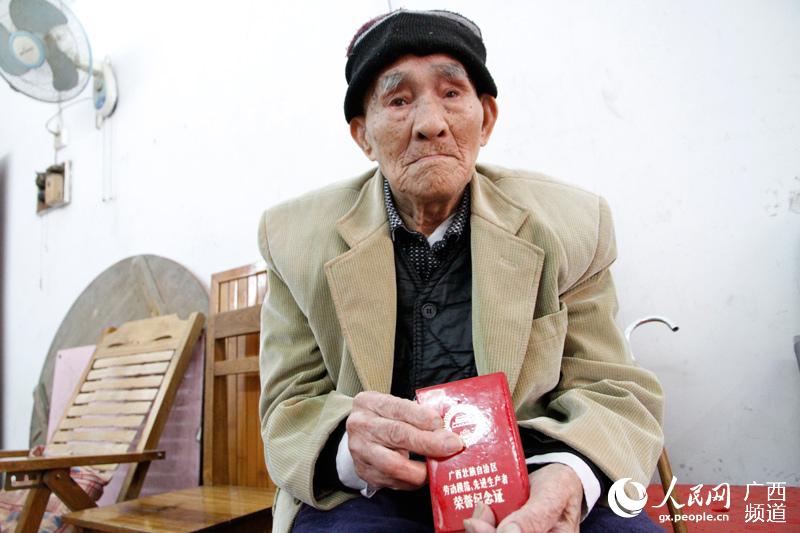 韦兆良老人向人们展示“劳模”荣誉纪念证书