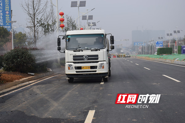 洒水车正在清洗路旁绿植和路面泥土。.jpg