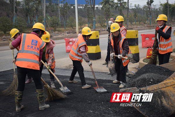 工作人员清理平整路面连接处，即将完成面层沥青铺设。.jpg