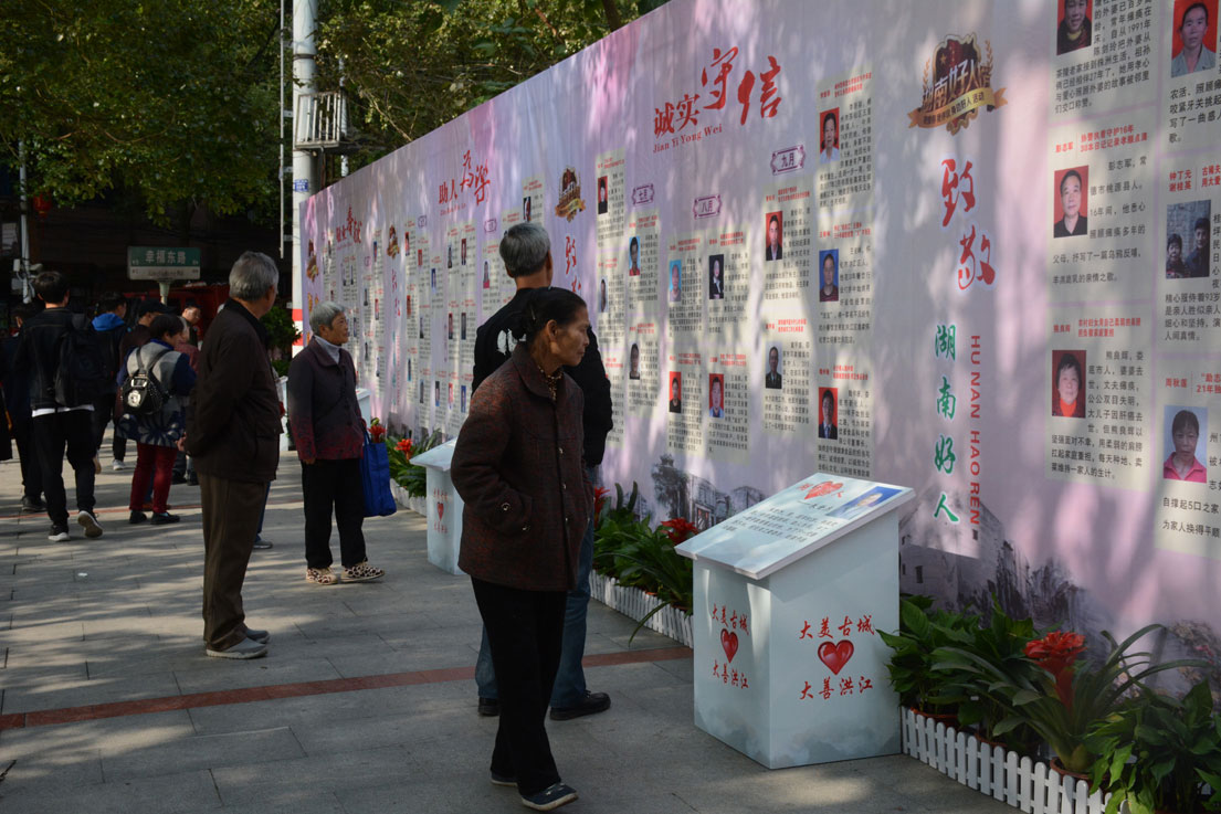在洪江区闹市街头,有一块属于好人模范的专属展板,吸引市民驻足观看.