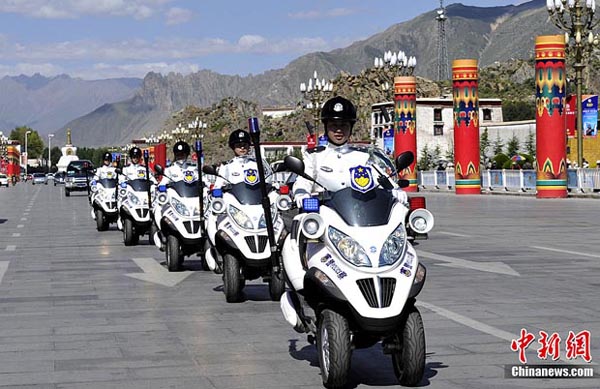 图为女交警骑着崭新的警用摩托车在布达拉宫广场前巡逻.