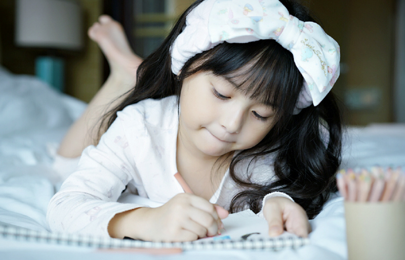 刘楚恬戴着白色的发带,趴在床上写信,表情十分认真呆萌